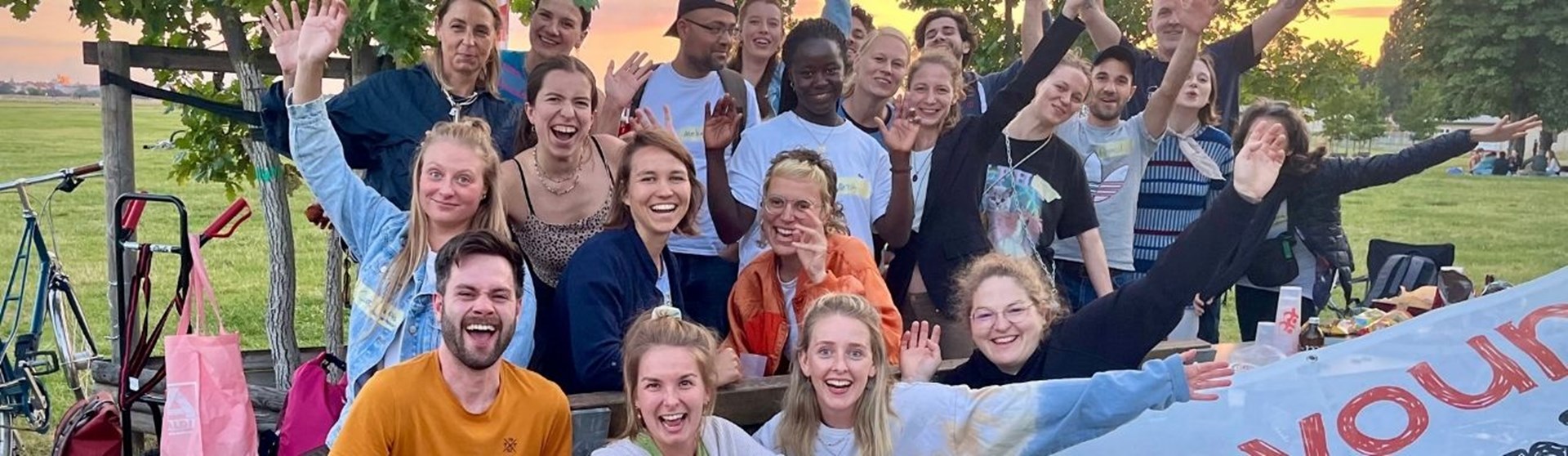 Mehrere Jugendliche lachen in die Kamera und strecken die Arme in die Luft.