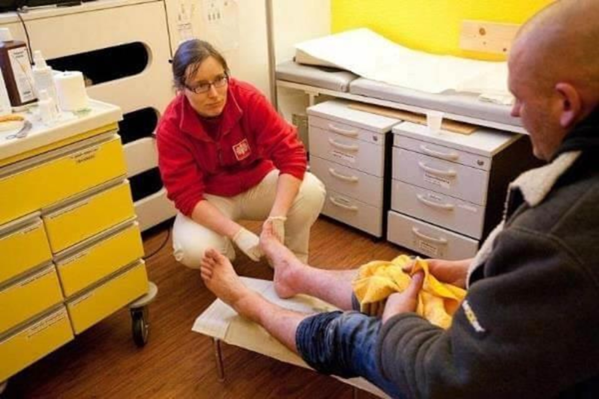 Krankenschwester kniet vor einem Patienten